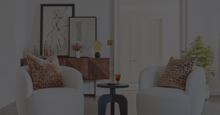 A living room with white chairs and colorful pillows